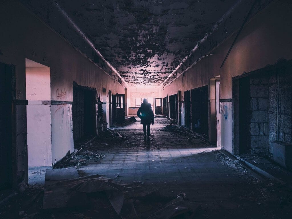 Person walking down hallway and destroyed building