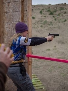 Woman holding and pointing a Glock outside